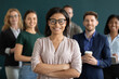 © fizkes - Multiethnic crew. Young biracial female confident qualified specialist hr ceo leader head member of diverse corporate team posing for portrait holding arms crossed on chest smiling looking at camera