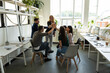 © fizkes - Celebrating success. Multiethnic millennial corporate staff and older woman trainer leader stacking hands in high five gesture greeting colleagues with business victory team achievement winning reward