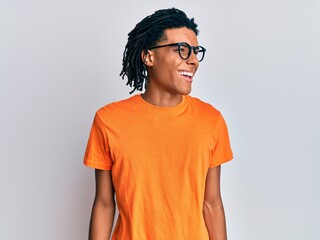 Wall Mural - Young african american man wearing casual clothes and glasses looking away to side with smile on face, natural expression. laughing confident.