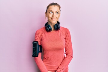 Poster - Beautiful caucasian woman wearing sportswear and arm band smiling looking to the side and staring away thinking.