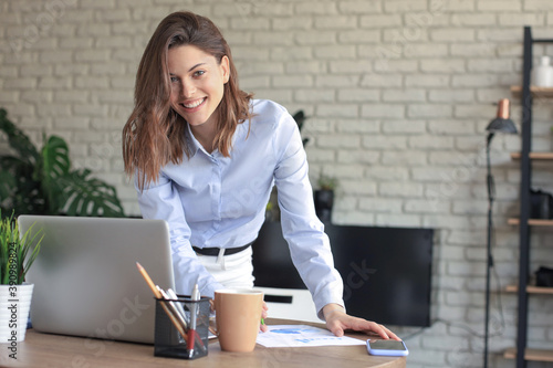 Obraz Dibond Young business woman standing in her home office writing notes.
