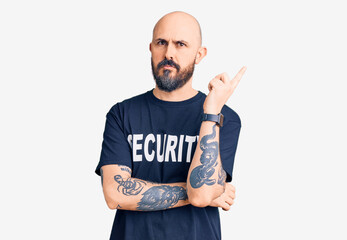 Sticker - Young handsome man wearing security t shirt pointing with hand finger to the side showing advertisement, serious and calm face