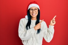 Beautiful Hispanic Woman Wearing Christmas Hat Smiling And Looking At The Camera Pointing With Two Hands And Fingers To The Side.