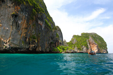 Big stone or rock mountain or island and long tail boat on sea with blue sky and white cloud background at Krabi, Thailand. Beauty in nature and Landmark for tourist travel in south of Thailand.