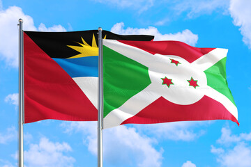 Burundi and Antigua and Barbuda national flag waving in the windy deep blue sky. Diplomacy and international relations concept.