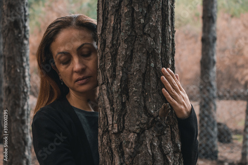 Fotografía The beautiful woman is hagging trees, Girl loves nature and standing in the autu