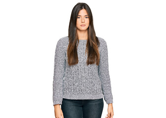 Wall Mural - Young brunette woman wearing casual winter sweater relaxed with serious expression on face. simple and natural looking at the camera.