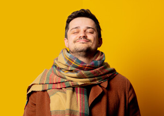 Style man in coat and scarf on yellow background