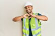 © Krakenimages.com - Handsome man with beard wearing safety helmet and reflective jacket smiling in love doing heart symbol shape with hands. romantic concept.
