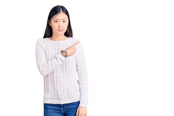 Sticker - Young beautiful chinese woman wearing casual sweater pointing aside worried and nervous with forefinger, concerned and surprised expression