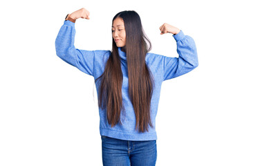 Poster - Young beautiful chinese woman wearing casual turtleneck sweater showing arms muscles smiling proud. fitness concept.