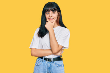 Young hispanic girl wearing casual clothes looking confident at the camera smiling with crossed arms and hand raised on chin. thinking positive.