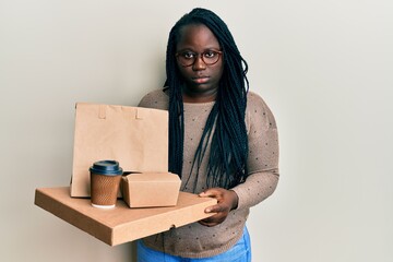 Sticker - Young black woman with braids holding take away food depressed and worry for distress, crying angry and afraid. sad expression.