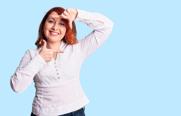 Sticker - Young beautiful redhead woman wearing casual shirt smiling making frame with hands and fingers with happy face. creativity and photography concept.