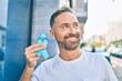 © Krakenimages.com - Middle age handsome man smiling happy holding blue prostate cancer ribbon at the city.