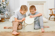 © Елена Лавринович - two eight-year-old boys are sitting in a bright New Year's interior. Children open gifts. Christmas and new year concept.