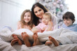 © alexkich - A family with children having fun on the bed under the covers during the Christmas holidays.