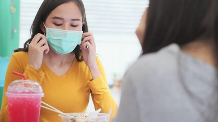 Wall Mural - Asian woman sitting separated in restaurant eating food .keep social distance for protect infection from coronavirus covid-19, restaurant and social distancing concept.