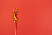 Overhand Knot With Orange Carabiner And Yellow Climbing Rope On Red Background