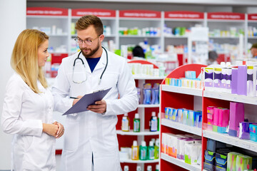 Wall Mural - team of young caucasian chemists or druggists discussing medicines, check medical indications, in white medical gowns, at work place