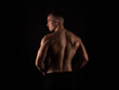 © Anetta - Handsome young bodybuilder with muscular back standing on black background