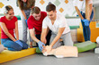© alfa27 - CPR class with young caucasian instructors speaking and demonstrating help first aid, cpr mannequin on the floor