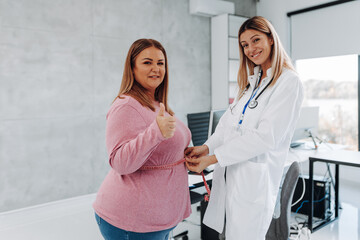 Wall Mural - Nutritionist measuring waist of overweight woman in weight loss clinic.