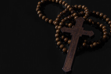 Wooden christian cross necklace on black background