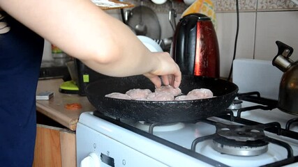 Wall Mural - cooking burger patties in a pan with butter. woman fries meatballs in oil on a hot pan. girl is cooking at home. quarantined food. Recipes and cooking. meatballs for burger meat cutlets in the kitchen