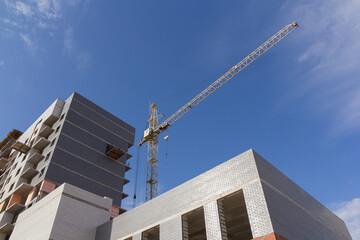 Poster - Construction crane against the blue sky during the construction of an apartment building