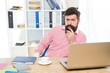 © be free - Bearded man with serious look sit at managers desktop in modern work room, office