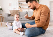 © Prostock-studio - Dad Spoon Feeding Baby During Paternity Leave At Home