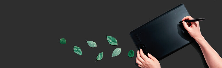 Graphic pen tablet with green leaves - flat lay