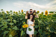 © Andriy Medvediuk - Beautiful couple in sunglases having fun in sunflowers field. A man and a woman in love walk in a field with sunflowers, a man hugs a woman. selective focus