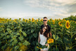 © Andriy Medvediuk - Beautiful couple in sunglases having fun in sunflowers field. A man and a woman in love walk in a field with sunflowers, a man hugs a woman. selective focus
