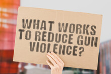 The Question " What Works To Reduce Gun Violence? " On A Banner In Hand. Human Holds A Cardboard With An Inscription. Recommendation. Crime. Control. Legislation. Law. Prohibition