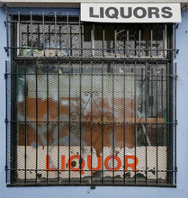 Barred Liquor Store Window In Rundown Section Of Town.