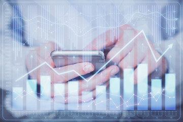 Double exposure of man's hands holding and using a digital device and forex graph drawing. Financial market concept.