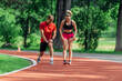 © qunica.com - Young couple stretching before starting their morning jogging routine on a tartan track at the park.