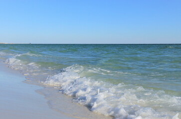 View of the Gulf Coast from the shore, green ocean, wave and wet sand, blue sky