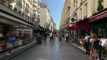 Time Lapse Footage Of People Walking And Sitting At Cafes On Famous Street Called "Rue Montorgueil" In Paris. It Is A Sunny Summer Day. Camera Moves Forward.
