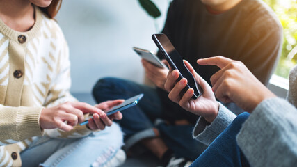 group of young people using and looking at mobile phone together