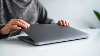 Closeup image of hands close and open a laptop computer on table after finished using it