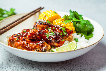 Wall Mural - Asian food concept. Sticky sesame  chicken with rice and vegetables in white plate, gray background.