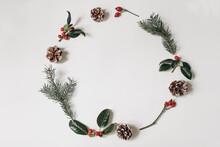 Christmas Circle Floral Composition. Wreath Of Holly Berry, Spruce Tree Branches, Pine Cones And Red Rose Hips Isolated On White Table Background. Winter Natural Arrangement. Flat Lay, Top View.
