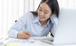 © Puwasit Inyavileart - Young white Asian woman studying via the internet in her home office.