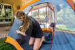 © Mint Images - Teenage girl and her younger brother setting up tent to sleep out during a staycation.