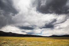 A Stormy Sky With Heavy Grey Clouds, Mountains In The Distance.  
