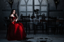 Bloodthirsty Female Vampire In Red Dress. Medieval Interior