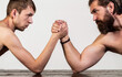 © Yevhen - Two man's hands clasped arm wrestling, strong and weak, unequal match. Heavily muscled bearded man arm wrestling a puny weak man. Arms wrestling thin hand, big strong arm in studio